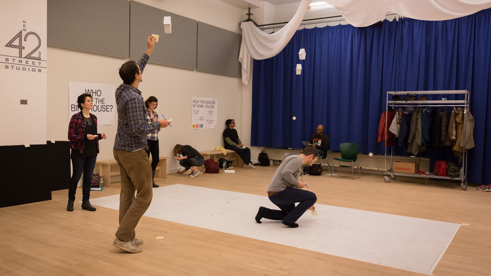 A group of people are scattered around a room participating in a professional development exercise with post-its.