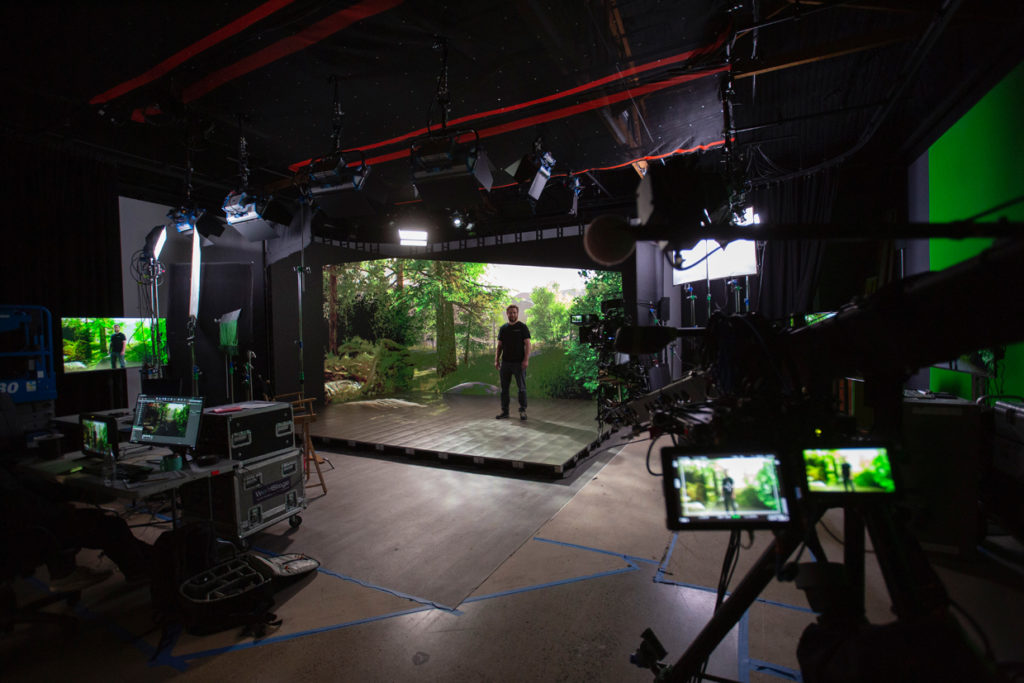 Man standing on an xRStage set with a forest background and cameras around.