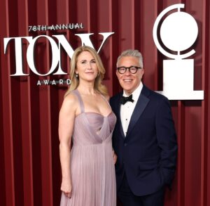 Fiona Rudin and Russell Granet standing in front of red velvet curtain with Tony logos