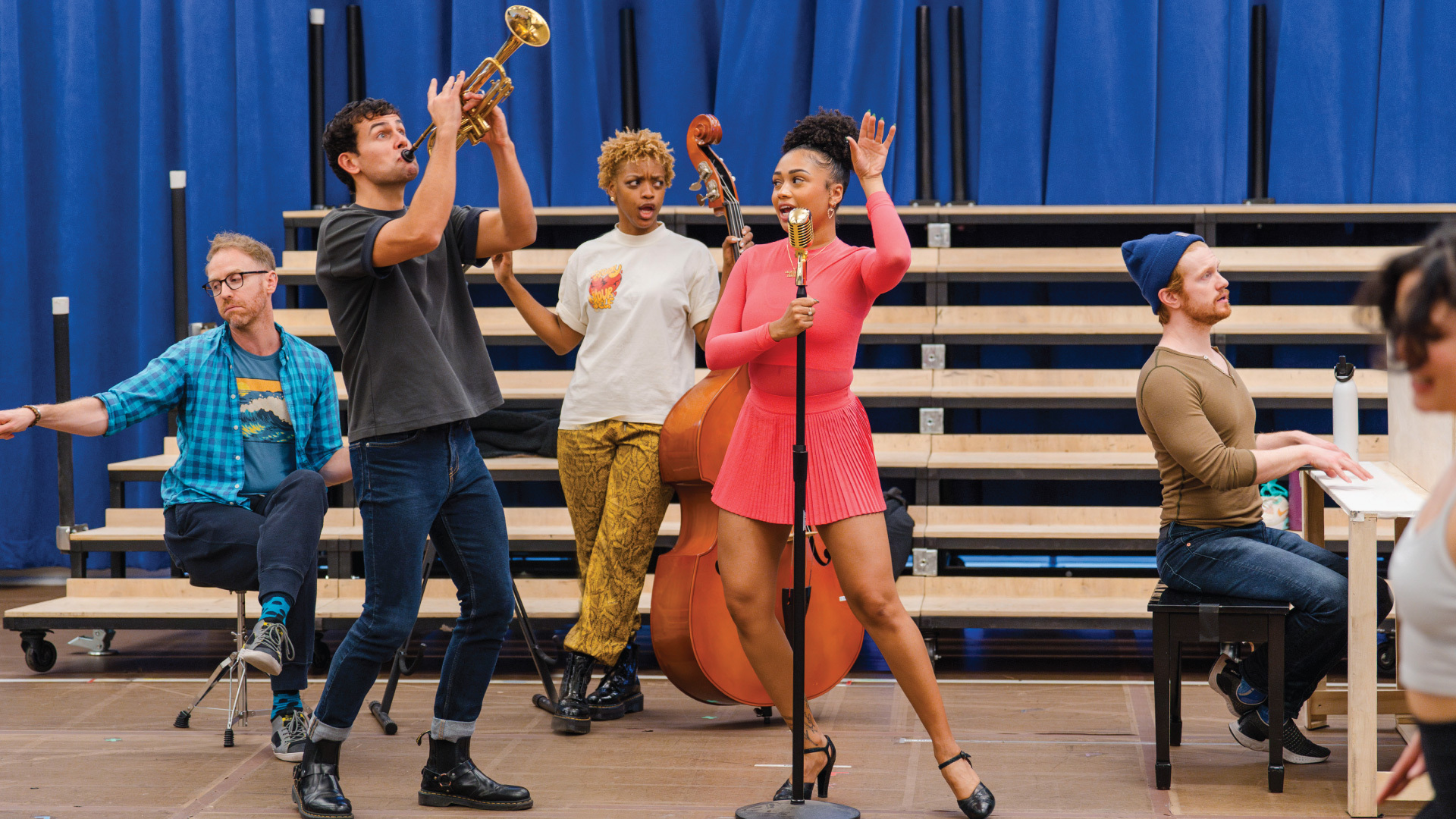 Trumpet player, bass player and pianist flank singer at a microphone stand